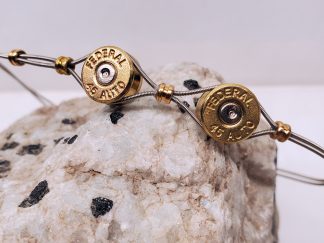 Double 45 ACP casings and guitar strings unisex bracelet shown on rock